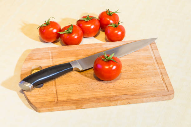 Tomatoes on the cutting board with knife.