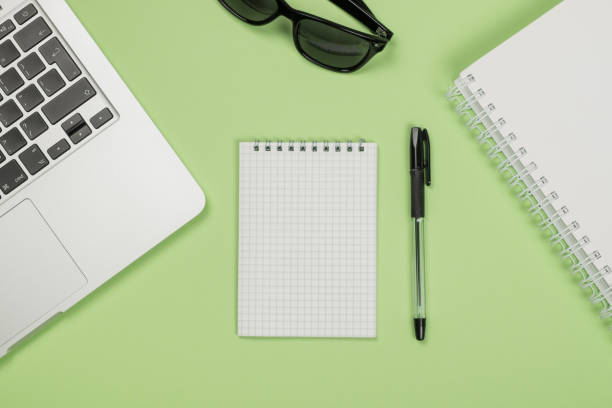 istock Modern office desk table with laptop, blank notebook page for input the text in the middle and other supplies. Top view, flat lay 654324152