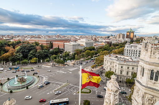 View of Square of Cibeles from Town Hall of Madrid at sunset. Spanish flag on foreground