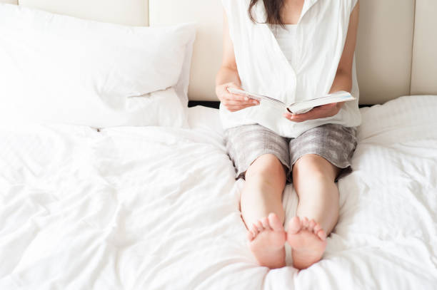 istock Japanese woman sitting up in bed, reading 654328588