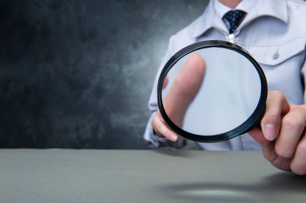 istock Japanese man wearing work clothes with a large magnifying glass in hand 654332048