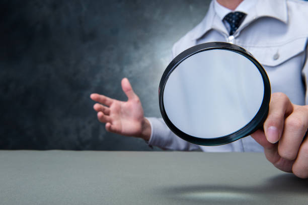 istock Japanese man wearing work clothes with a large magnifying glass in hand 654332056