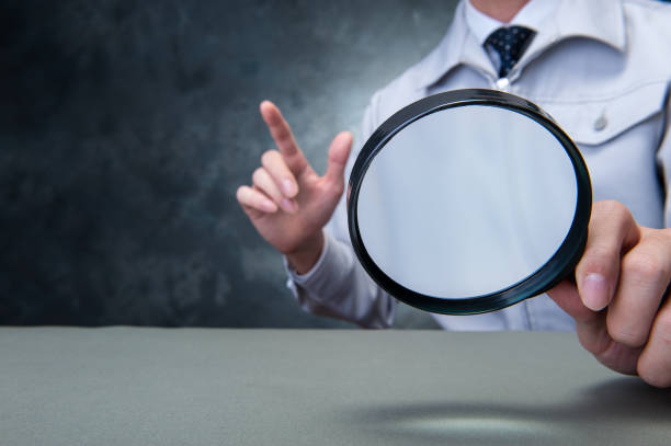 istock Japanese man wearing work clothes with a large magnifying glass in hand 654332070