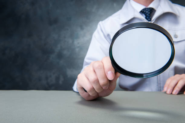 istock Japanese man wearing work clothes with a large magnifying glass in hand 654332074