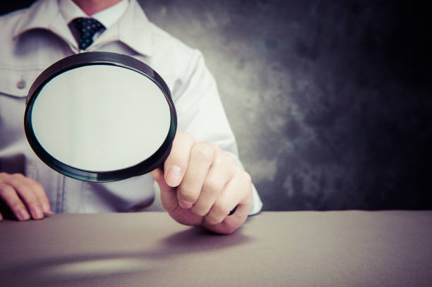 istock Japanese man wearing work clothes with a large magnifying glass in hand 654332088