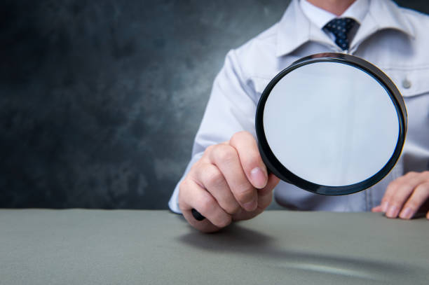 istock Japanese man wearing work clothes with a large magnifying glass in hand 654332094