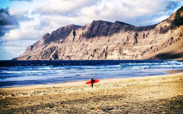 caleta de famara surf stół czerwony nierozpoznawalny lanzarote - famara zdjęcia i obrazy z banku zdjęć