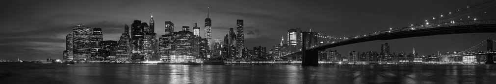 New York city with Brooklyn Bridge, iconic skyline panorama at night in black and white, high detailed