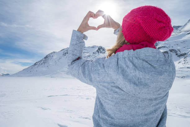 istock Young woman on ski slopes making heart shape 654350402