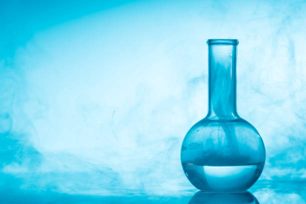 Chemical glass test tube with liquid and steam or smoke on blue background with copy space