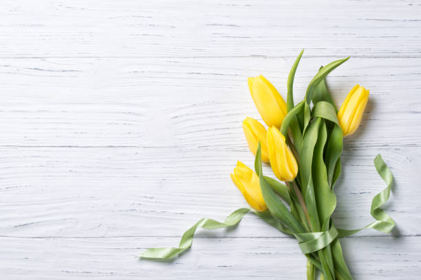 istock Yellow tulips bouquet on wooden background, top view with copy space 654358058