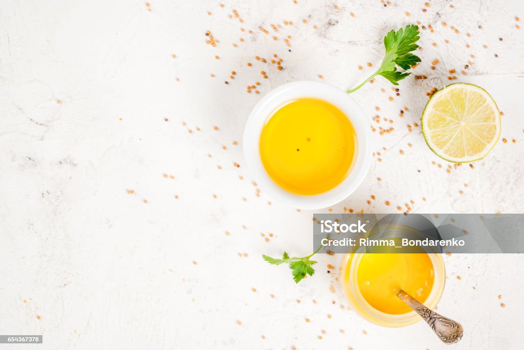 Ingredients for spring salad dressings Ingredients for cooking healthy light dressings for vegetable salad: lemon (lime), olive oil, mustard, greens, on white concrete table, copy space top view Vinaigrette Dressing Stock Photo