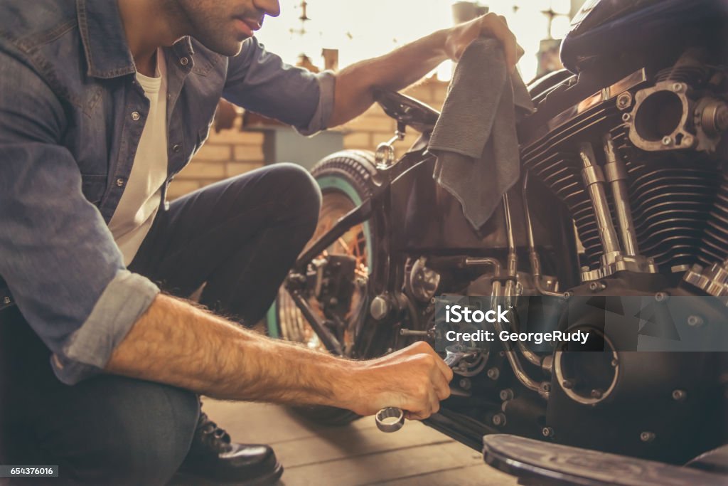 Motorbike repair shop Attractive man is repairing a motorcycle in the repair shop Motorcycle Stock Photo