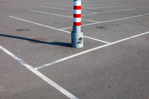 Red and white posts, fences in the city parking lot, a sunny day. The area is fenced off with iron posts painted red and white. Space for copy, text and advertising