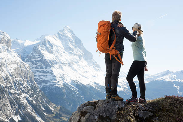 istock Hikers look out to snowy mountains at ridge crest 654401657