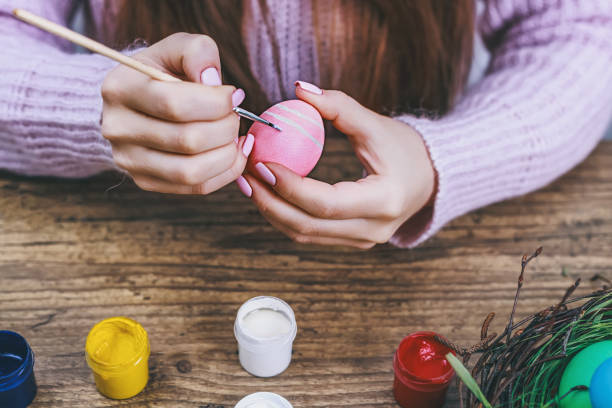 istock Female hands painting Easter eggs on wooden table. Toned picture 654401702