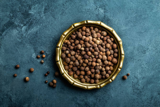 Allspice pepper, peppercorns on dark culinary background, top view, copy space