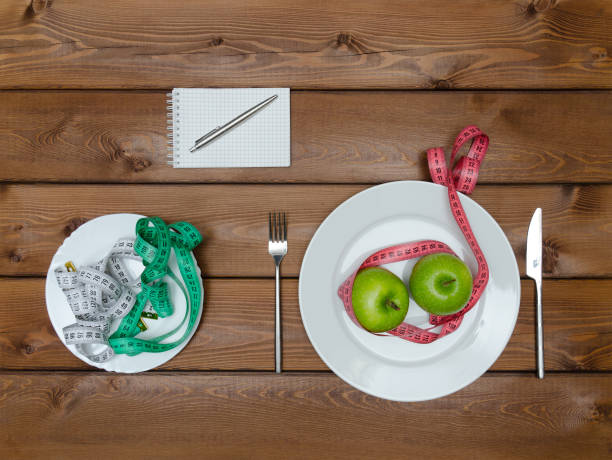 istock Green apples on plate with knife fork and measure tapes 654414752