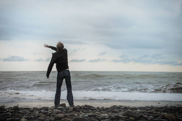 istock Young man standing on the sea shore 654440176