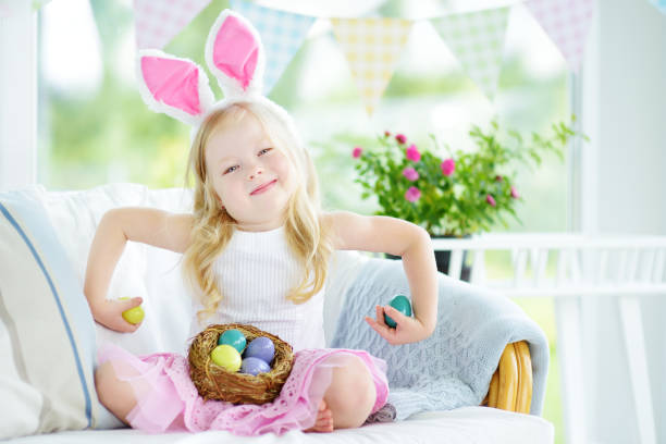 istock Cute little girl wearing bunny ears playing egg hunt on Easter 654448122