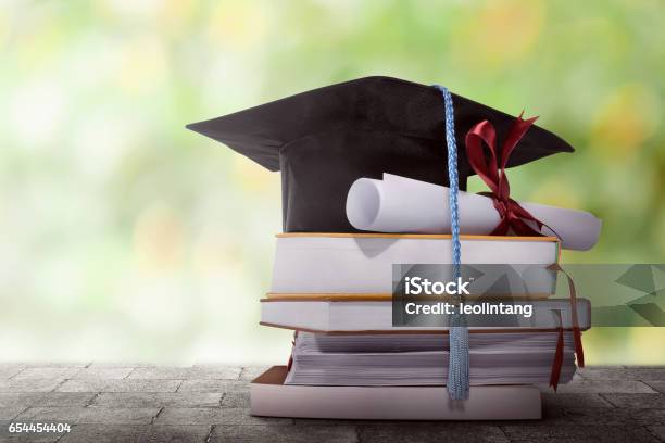 Sombrero De Graduación Grado Papel En Una Pila De Libros Foto de stock y más banco de imágenes de Universidad