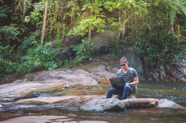 istock Hiker backpack with laptop and phone at  waterfall  the forest. 654473062