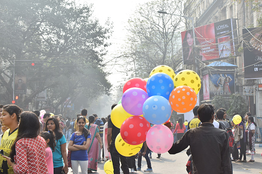 Unidentified man selling balloons to city children on blocked, otherwise busy, Park Street for 