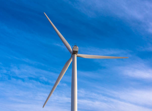 istock Lone wind turbine generator with a bright blue sky background 654481890