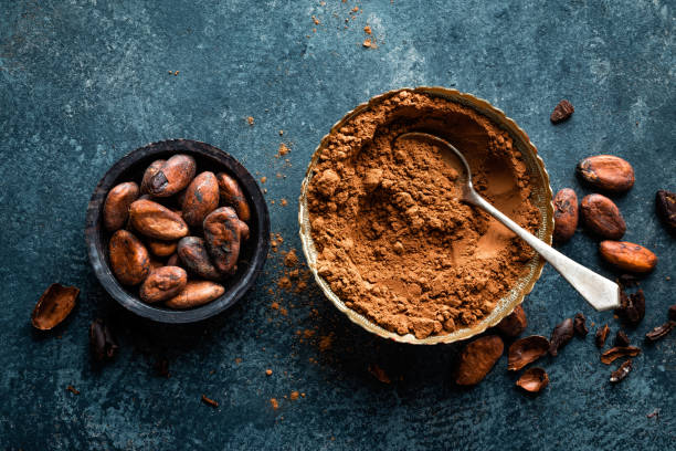 Cocoa powder and cacao beans on dark background, top view Cocoa powder and cacao beans on dark background, top view cacao fruit stock pictures, royalty-free photos & images