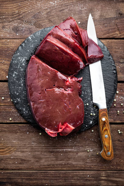 istock Raw liver on slate board on wooden background top view 654547900