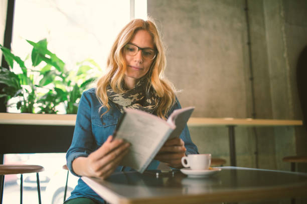 istock Woman reading book in cafe 654555290