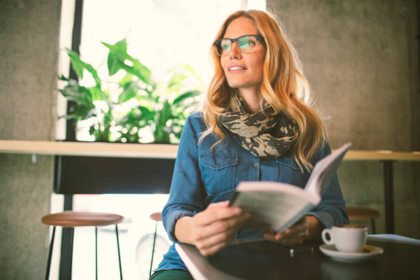 istock Woman reading book in cafe 654555332