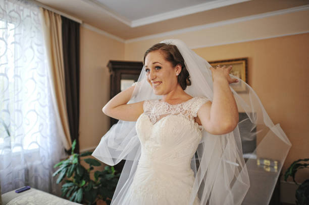 istock Charming smiled bride with veil stay at her room 654567034