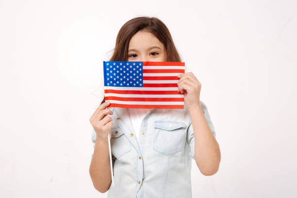 istock Shy child holding American symbolic in the studio 654573132