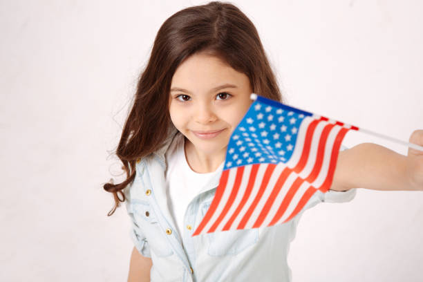istock Playful girl holding American flag in the studio 654573238