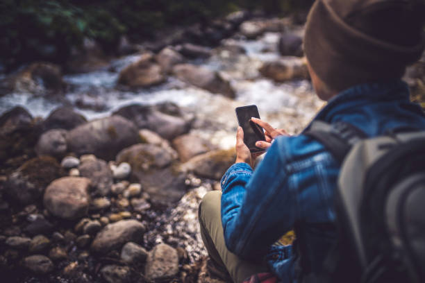 istock Young woman using a smartphone in the forest 654581240