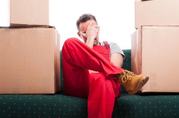 istock Tired mover man sitting on couch with cardboard boxes around 654591928
