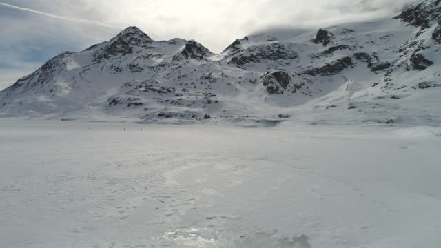 Drone flies over frozen mountain lake
