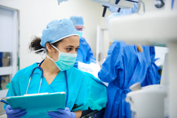 Female anaesthesiologist writing the updates Female anaesthesiologist writing the updates critical care photos stock pictures, royalty-free photos & images