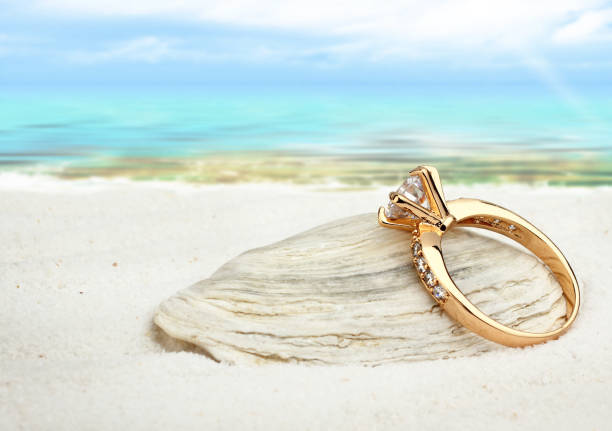 istock Jewellry ring with big diamond on sand beach, soft focus 654636414