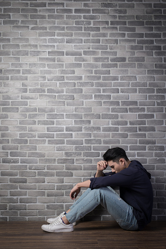 man sit and feel depressed with brick wall ,asian