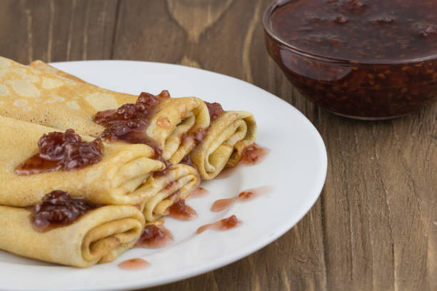 Pancakes or Russian Blintzes with jam on a wooden background