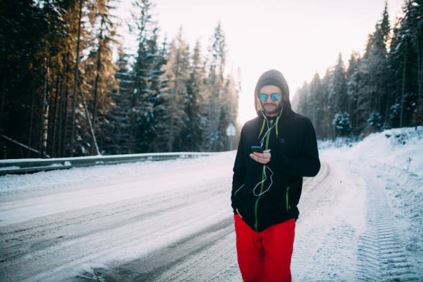 Handsome man with phone standing on a road in the snow forest stock photo