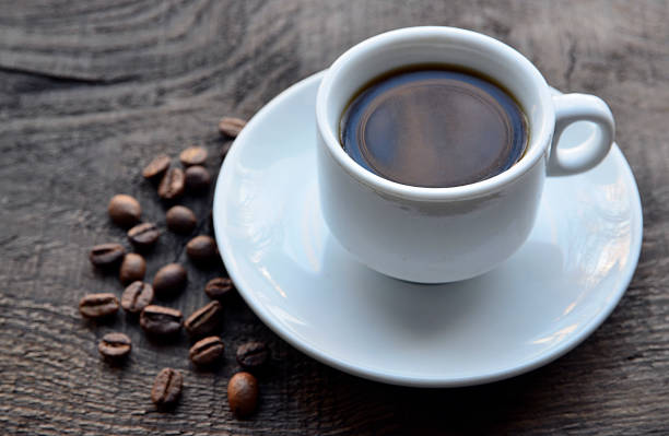 istock Coffee cup with beans on old rustic wooden table.White coffee mug. 654655796