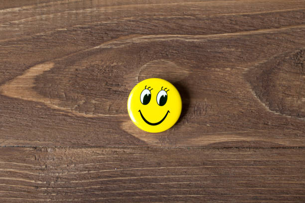 istock Yellow buttons with smiley faces on a wooden background 654658650