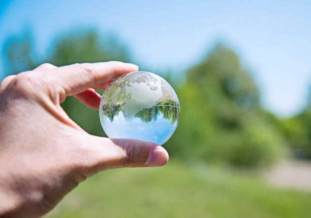 Hand holding a glass globe in nature.