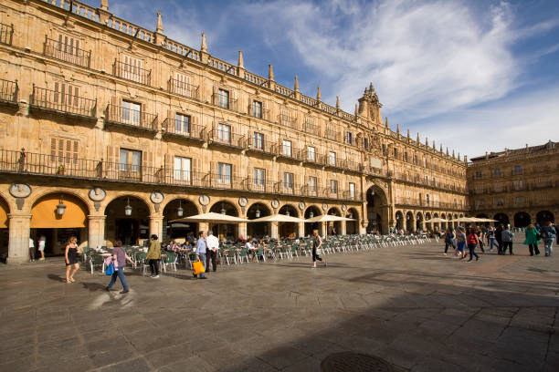 People sit and walk on the historical Plaza Mayor,or main square, with tables and chairs of a restaurant in the old center of Salamanca, Spain on June 2, 2016