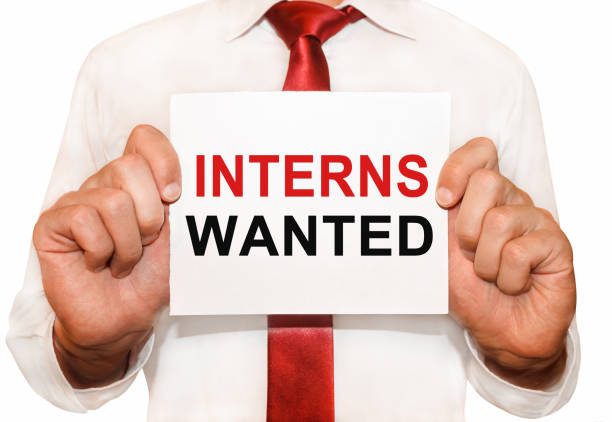 istock Man holding a card with a text Interns Wanted 654668656