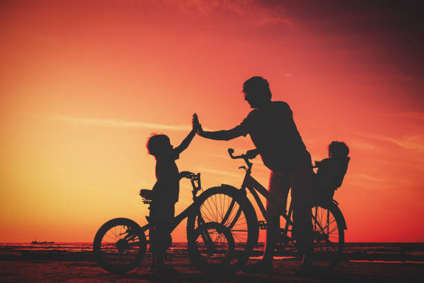 istock father with two kids on bikes at sunset 654680040