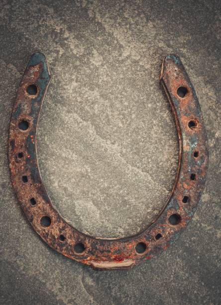 istock Old rusty horseshoe on natural stone background. 654680088